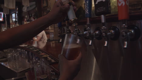 Close-up-view-of-bartender-pouring-beer-from-tap