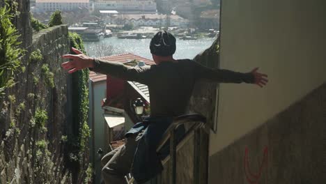 Establishing-Shot,-Man-slides-on-the-rails-in-an-alley-of-Porto,-Douro-river-In-the-background