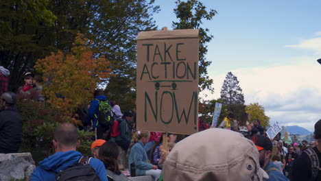 A-Female-Protester-Holds-a-Sign-that-Reads-"TAKE-ACTION-NOW