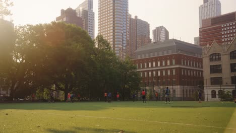Wide-shot:-Two-Teams-playing-soccer-on-field-in-front-of-skyscraper-Buildings-in-New-York-at-sunset---Static