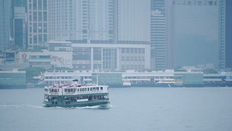 Star-Ferry-Fährt-Durch-Den-Victoria-Harbour-In-Hongkong-Mit-Modernen-Gebäuden-Im-Hintergrund-–-Mittlere-Aufnahme