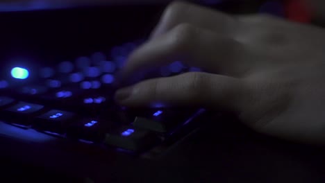 The-steady-4k-recording-shows-an-unrecognizable-person-is-playing-writing-on-a-blue-illuminated-keyboard-using-the-keys-of-the-keyboard