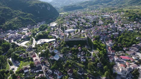 Aerial-orbiting-shot-over-the-Walled-City-of-Jajce-and-Jajce-Fortress-on-steep-hill,-Bosnia-and-Herzegovina