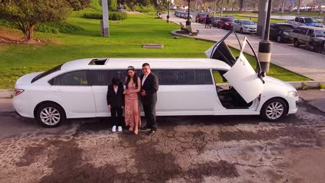 Girl-taking-photos-with-her-family-during-her-birthday-celebration-in-front-of-a-white-limousine-during-sunset