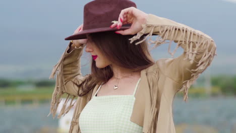 White-stylish-woman-gracefully-holding-cowboy-hat,-model-posing-at-dusk---Slow-motion-closeup