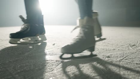 Slowmotion-of-couple-of-slihouttes-ice-skating-on-a-snow-covered-winter-stadium