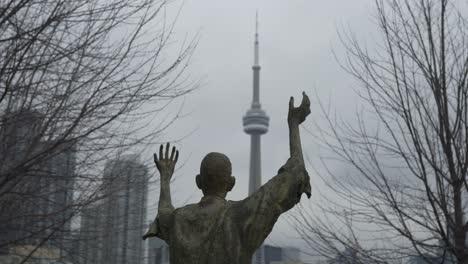 Statue-Eines-Jubelnden-Mannes-Im-Vordergrund-Des-CN-Tower-An-Einem-Bewölkten-Tag-In-Toronto