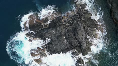 Cinematic-top-down-aerial-shot-of-strong-ocean-waves-breaking-on-coastal-rugged-rocks-in-Catanduanes,-Bicol