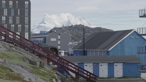 Ein-Paar,-Das-Draußen-Neben-Blauen-Gebäuden-In-Grönland-Eine-Rote-Treppe-Hinuntergeht