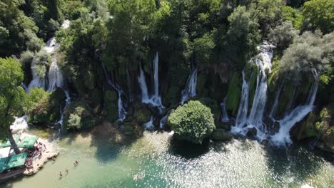Aerial-static-shot-of-beautiful-Kravica-Waterfall-with-people-Swiming-and-sunbathing,-Bosnia-and-Herzegovina