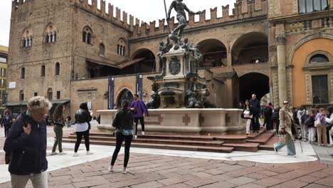 Touristen,-Die-Vorbeigehen-Und-Selfies-Am-Neptunbrunnen-Mit-Palazzo-Re-Enzo-Im-Hintergrund-In-Bologna,-Italien-Machen