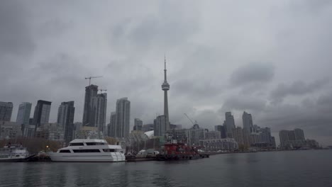 CN-Tower,-skyline-and-waterfront-in-cloudy-Toronto,-slow-zoom-out