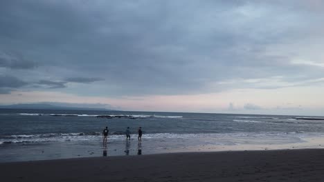 Friends-Fishing-Alone-at-the-Stormy-Black-Sand-Beach-of-Bali-Indonesia,-Dark-Blue-Silver-Skyline,-Saba,-Gianyar
