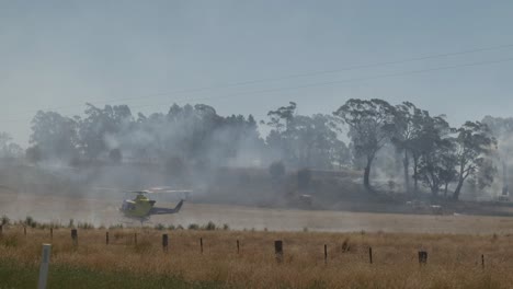 Hubschrauber-Saugt-Dammwasser-Auf,-Im-Hintergrund-Feuerwehr-Und-Löschfahrzeuge