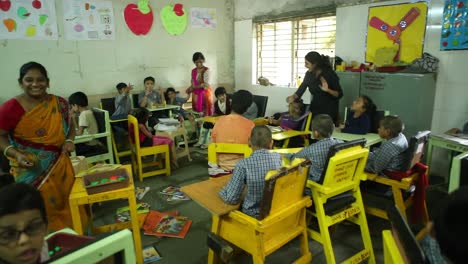 Eine-Kamera-Bewegt-Sich-Vorwärts-Zu-Einem-Grundschulklassenzimmer-Einer-NGO,-In-Dem-Kinder-Lernen-Und-Lehrer-Durch-Geschichten-Lehren,-Bis-Hin-Zur-Bildung