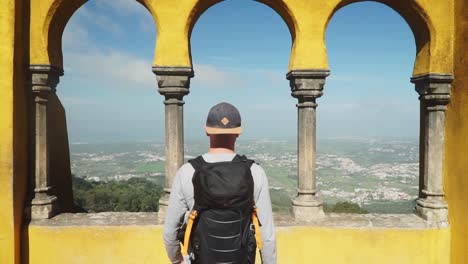 Medium-Trucking-shot,-Man-moveing-towards-view-deck-between-the-pillars-on-Pena-National-Palace-in-Portugal