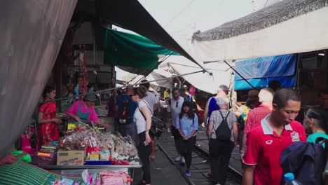 Establishing-Shot,-Tourists-walking-and-checking-different-shops-in-the-Maeklong-Trail-Road-Market-in-Thailand