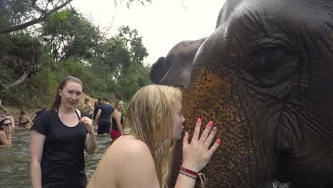 Female-Tourist-Kissing-Friendly-Elephant-in-River-of-Thailand-National-Park,-Close-Up