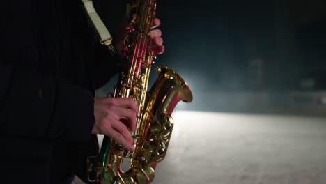 Cámara-Lenta-De-Un-Saxofonista-Tocando-Una-Canción-En-Un-Estadio-De-Invierno-Cubierto-De-Nieve-Con-Patinadores-Sobre-Hielo-Al-Fondo