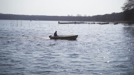 Ein-Mann-Fährt-In-Einem-Motorboot-über-Das-Idyllische,-Tiefblaue-Wasser,-Das-Das-Einfallende-Sonnenlicht-Traumhaft-Reflektiert