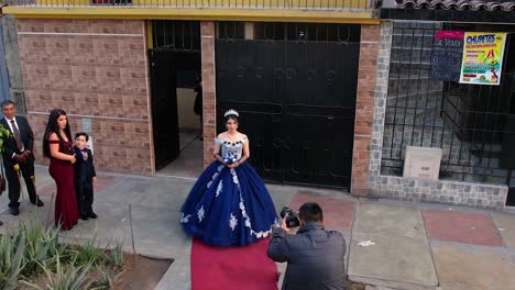 Man-taking-photos-of-a-girl-in-a-blue-dress-witha-tiara-and-a-bouquet-before-a-party