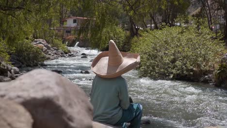 Person-Resting-Sitting-On-Rock-Enjoying-Streaming-River-Water,-Obrajillo,-Peru