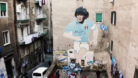 Aerial-tilt-up-showing-mural-of-famous-Diego-Maradona-on-house-wall-in-city-of-naples