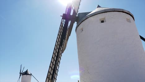 Slow-motion-shot-of-windmill-blade-rotor-moving-in-front-of-the-sun,-location-is-Consuegra-in-Spain,-the-place-of-Don-Quijote-and-Money-Heist,-Casa-De-Papel