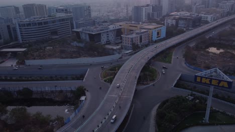 Drone-orbiting-at-the-Mindspace-Rotary-Junction-revealing-the-Mindspace-roundabout-road-Flyover-at-early-morning,-Hyderabad