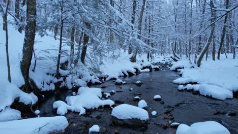 Beautiful-smooth-low-drone-footage-of-a-snowy-stream-in-a-winter-wonderland