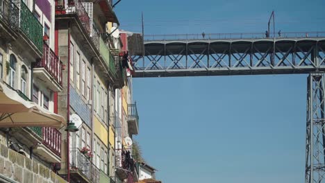 Up-Trucking-right-shot,-Old-Town-Building-reveals-the-Dom-Luis-Bridge,-People-walking-on-the-bridge-in-the-background