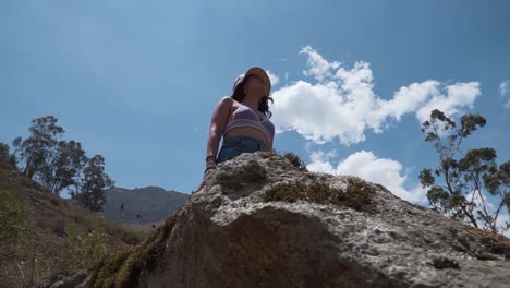 Low-Angel-Shot-Of-Beautiful-Lady-Standing-On-High-Big-Rock-In-Nature,-Obrajillo,-Peru