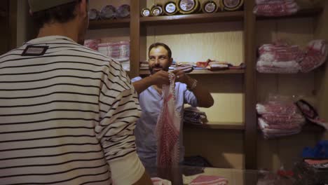 Tourist-buying-authentic-local-fabric-rug-from-market-vendor-in-Madaba,-Jordan