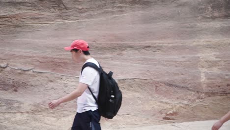 Male-tourist-running-and-jumping-off-wadi-desert-canyon-wall-Petra-Jordan