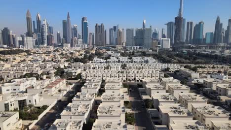 Luftüberführung-Eines-Vorort-Wohngebiets-Von-Dubai-Und-Skyline-Im-Hintergrund-An-Einem-Sonnigen-Tag-Mit-Blauem-Himmel---Nach-Oben-Geneigte-LKW-Aufnahme