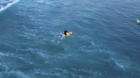 Aerial-view-of-a-man-paddleboarding-in-the-ocean-with-his-friends-during-the-day