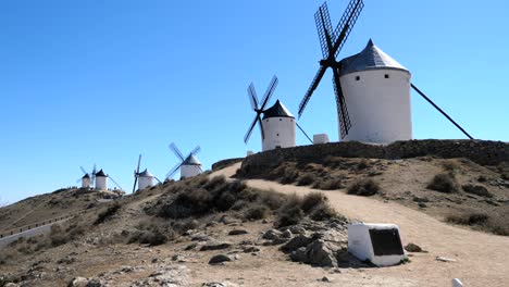 Windmills-landscape-in-Spain,-over-a-lush-hill-on-blue-sky-background-in-a-spring-day