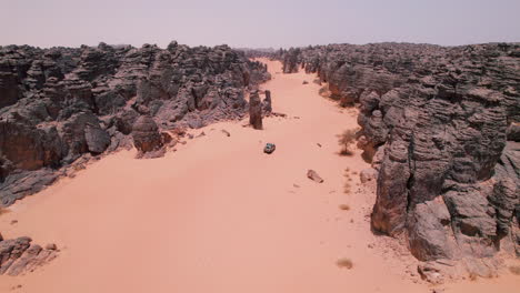 Vehicle-Driving-Off-Road-In-The-Desert-In-Tassili-N'Ajjer-National-Park,-Algeria---Aerial-Drone-Shot