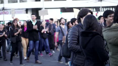 Women-and-men,-mostly-wearing-black,-are-holding-signs-and-marching-together-during-the-International-Women's-Day-in-Quito