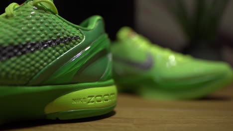 Zapatos-Nike-Kobe-6-Protro-Grinch-2020-Verdes-Filmados-Sobre-Una-Mesa-Marrón-Con-Fondo-Oscuro