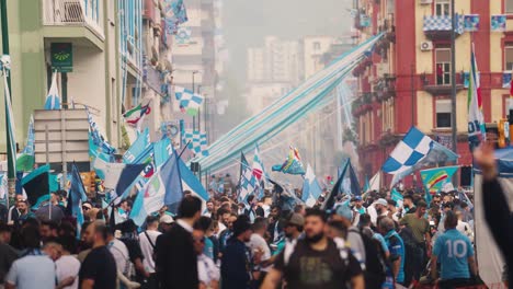 Wide-shot-showing-crowd-of-Italian-fans-on-road-celebrating-win-of-SSC-Napoli-in-Serie-A---Waving-flags-on-road-in-city-of-Naples,Italy
