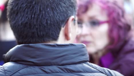 A-man-wearing-glasses-is-talking-to-a-woman-with-purple-hair-and-glasses-during-a-march-and-protest