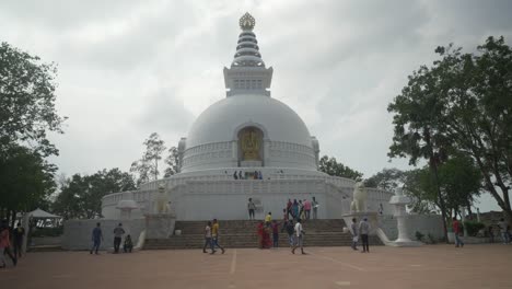 Touristen,-Die-Durch-Das-Gelände-Des-Buddhistischen-Denkmals-Vishwa-Shanti-Stupa-Am-Ratnagiri-Hügel-Mit-Einer-Buddha-Statue-In-Der-Mitte-Spazieren