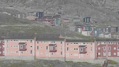 Vista-De-Cerca-De-Apartamentos-De-Color-Rojo-Y-Rosa-En-Nuuk-Con-Un-Paisaje-Montañoso-Al-Fondo