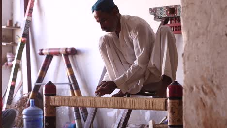 Männlicher-Pakistanischer-Arbeiter,-Der-In-Einer-Werkstatt-In-Sindh,-Pakistan,-Das-Traditionelle-Holzbett-Namens-Charpai-Webt