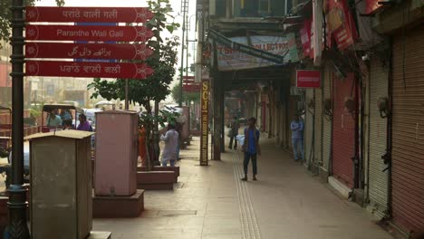 The-famous-Paranthe-Wali-Gali-name-board-at-the-street-of-Chandni-Chowk,-daily-wage-labours-working-early-in-the-morning