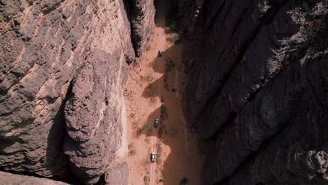 Aerial-View-Of-Off-road-SUV-Cars-Driving-Between-The-Sandstone-Cliffs-In-Tassili-n'Ajjer-National-Park-In-Djanet,-Algeria