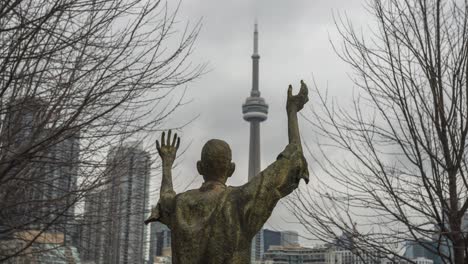 Timelapse-of-clouds-by-CN-Tower-behind-Jubilant-Man-statue-in-Toronto