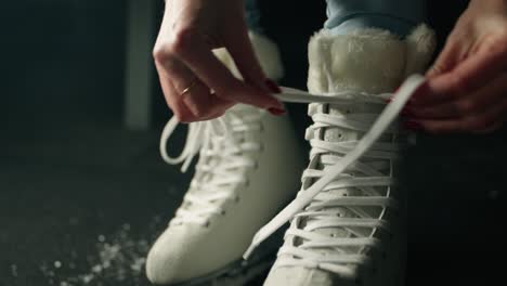 Slowmotion-of-woman-ice-skater-hands-making-a-knot-on-a-white-ice-skate-lace-with-blue-jeans