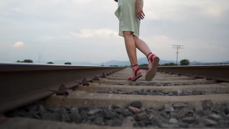 Junge-Frau-Im-Sommerkleid-Und-Roten-Sandalen-Modelliert-Sinnlich-Auf-Bahngleisen---Mittlere-Zeitlupenaufnahme-Aus-Niedrigem-Winkel